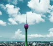 green and pink tower under blue sky and white clouds